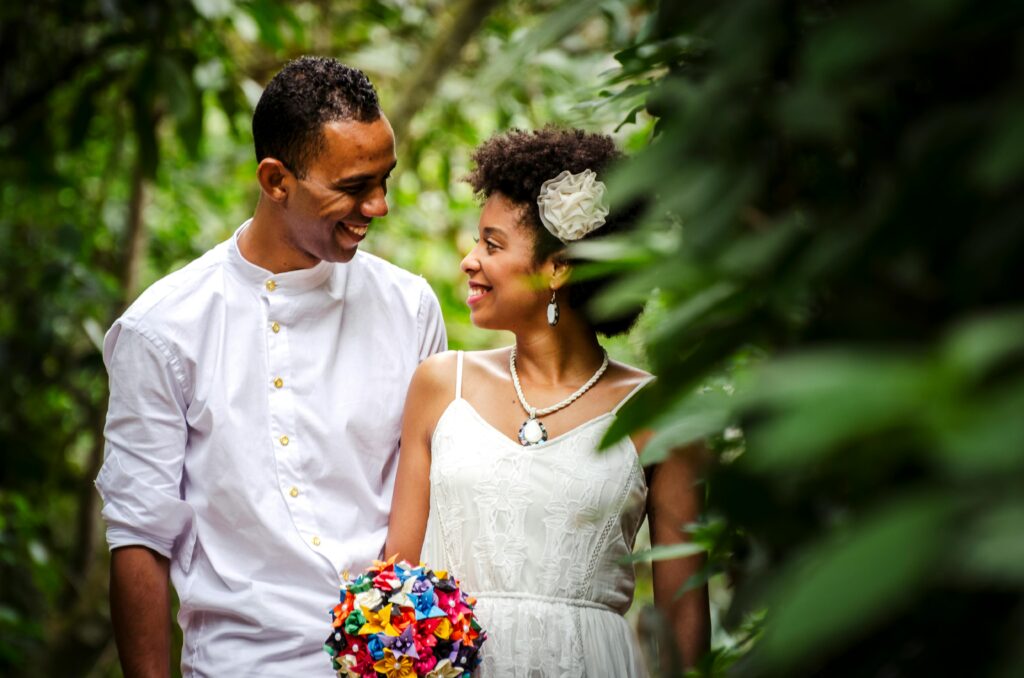 Happy Kenyan couple in wedding attire sharing a joyful moment outdoors.