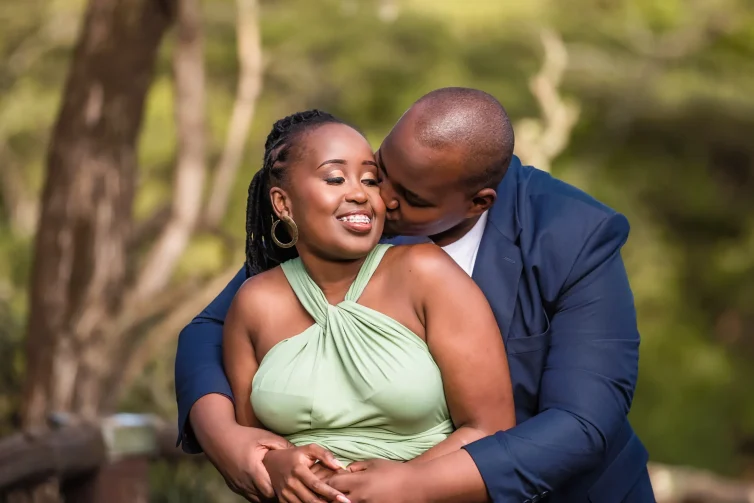 Romantic Kenyan wedding photo of couple embracing outdoors in lush greenery.